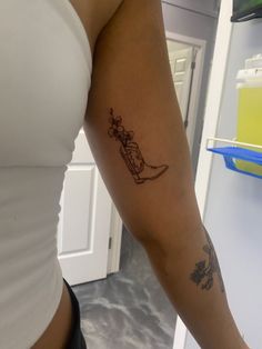 a woman's arm with a tattoo on it, in front of a refrigerator