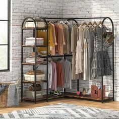 an open closet with clothes hanging on racks and baskets in front of a brick wall