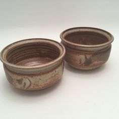 two brown and white bowls sitting on top of a white table next to each other