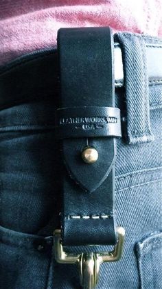 there is a black belt on the back of someone's jeans and it says leather works