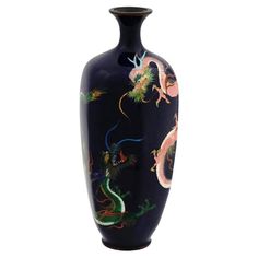 a black vase with colorful dragon designs on it's sides and bottom, in front of a white background