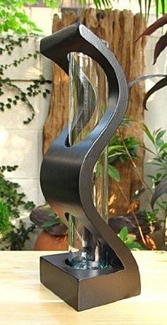 a metal sculpture sitting on top of a wooden table next to a potted plant