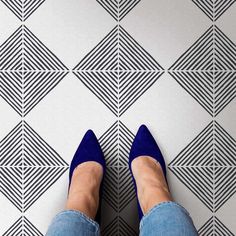 a woman's feet in blue shoes standing on a tiled floor