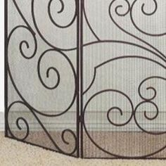 an iron gate with swirl designs on the sides is shown in front of a carpeted floor