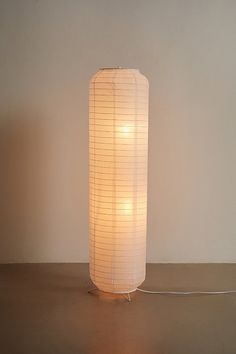 a white lamp sitting on top of a wooden table next to a wall and floor