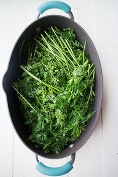 a pot filled with green vegetables on top of a white table