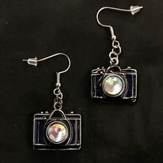 pair of camera earrings on black background