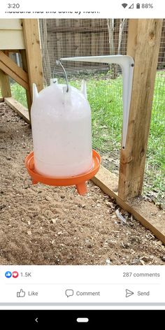 an orange and white container sitting on top of a dirt ground next to a wooden fence