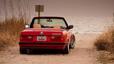 a red convertible car parked on the beach