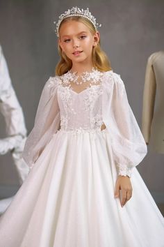 Make her first Communion one to cherish forever in the Pentelei Couture 3509 Communion Gown. This elegant dress combines sophistication and sweetness with its luxurious lace bodice, sheer lace long sleeves, and sparkle floor length skirt. This memorable Communion dress is perfect for making your daughter's first Holy Communion extra special. The timeless design flatters girls of all ages while allowing her inner radiance to shine through. Let her begin this important faith milestone feeling beau Girls Communion Dresses, Puffed Long Sleeves, First Communion Dress, Custom Gown, Girls Pageant Dresses, Communion Dresses, Stunning Gowns, Pageant Dresses, Ball Gown Dresses