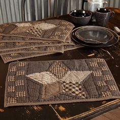 four quilted placemats sitting on top of a table next to plates and cups