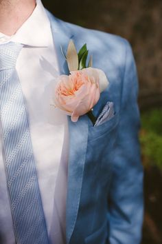 a man in a blue suit with a pink flower on his lapel