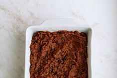 a white dish filled with brownie batter on top of a counter