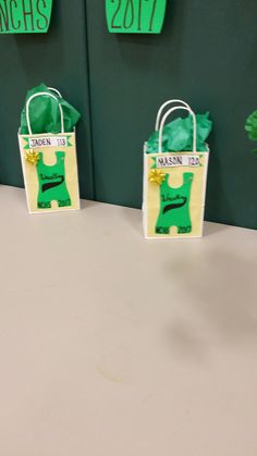 three bags with green and yellow designs on them sitting on a white table next to each other