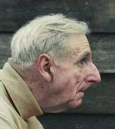 an older man with white hair is looking off into the distance while wearing a tan sweater