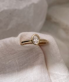 a gold ring with a white diamond on it sitting on top of a piece of cloth