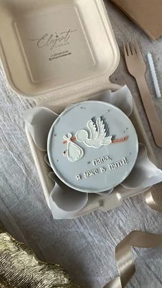 a baby's first birthday cake in a styrofoam box with spoons and forks