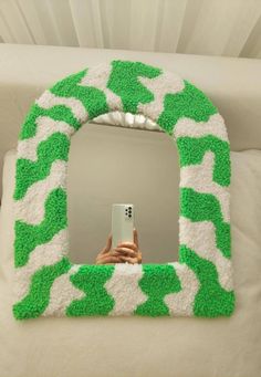 a person holding a cell phone in front of a green and white animal print mirror