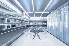 a glass table sitting in the middle of a room filled with white walls and shelves