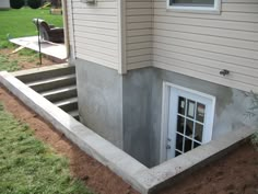 a house that is under construction with concrete steps leading up to the door and windows