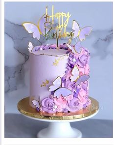 a birthday cake decorated with purple flowers and butterflies on a gold plated platter