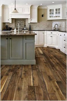 a large kitchen with white cabinets and wood flooring in the center, along with an island