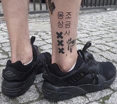 a man with a tattoo on his leg wearing black nike air max sneakers and writing