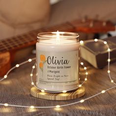 a white candle sitting on top of a table next to a string of lights and a guitar