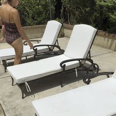 a woman in a bathing suit standing next to two lounge chairs