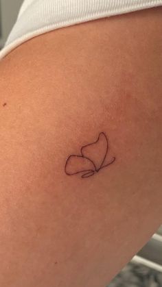 a small tattoo on the back of a woman's thigh with a heart in it