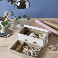 an open box sitting on top of a wooden table next to a lamp and other items