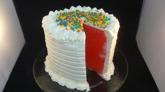 a cake with white frosting and colorful sprinkles on the top is sitting on a glass plate