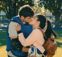 a man and woman kissing each other in the park