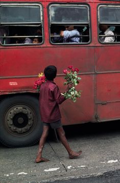 a young boy is walking past a bus with flowers