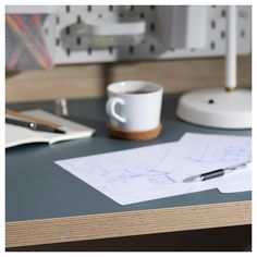 a cup of coffee sitting on top of a desk next to a pen and paper