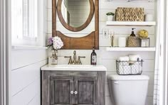 a white toilet sitting next to a bathroom sink under a wooden mirror mounted on a wall