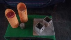 two vases sitting on top of a green table next to a small house and bottle