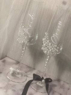 two wine glasses sitting on top of a counter next to a black ribbon and bow