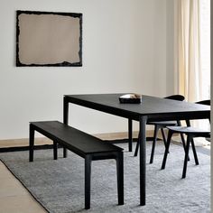 a black table and bench in a white room