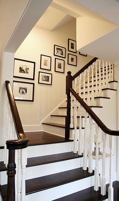 the stairs in this house are white and brown with pictures hanging on the wall above them