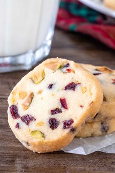 two cranberry white chocolate chip cookies next to a glass of milk