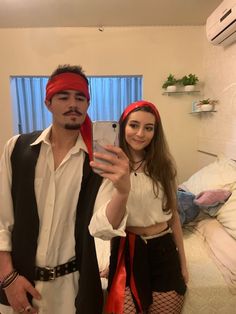 a man taking a selfie with a woman dressed up as pirate and holding a cell phone