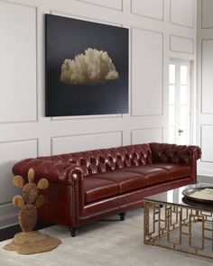 a living room with a red leather couch and coffee table in front of a painting on the wall