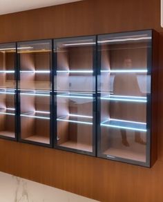 an empty glass display case in the middle of a room with marble counter tops and wooden walls