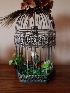 a birdcage with flowers in it sitting on a table