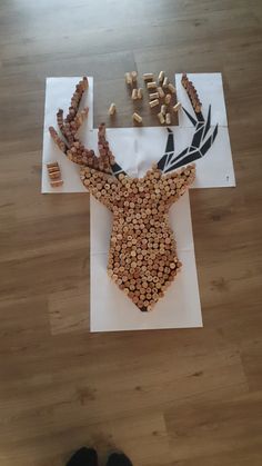 a deer head made out of wine corks on top of a wooden floor next to a pair of black shoes