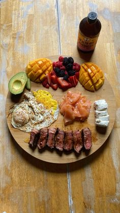 a wooden plate topped with meat, fruit and veggies next to a bottle of ketchup