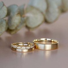 two gold wedding rings sitting next to each other