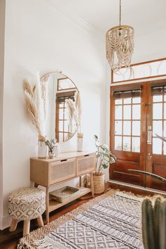 a living room with a rug, table and mirror