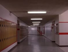 an empty hallway with red and white lockers